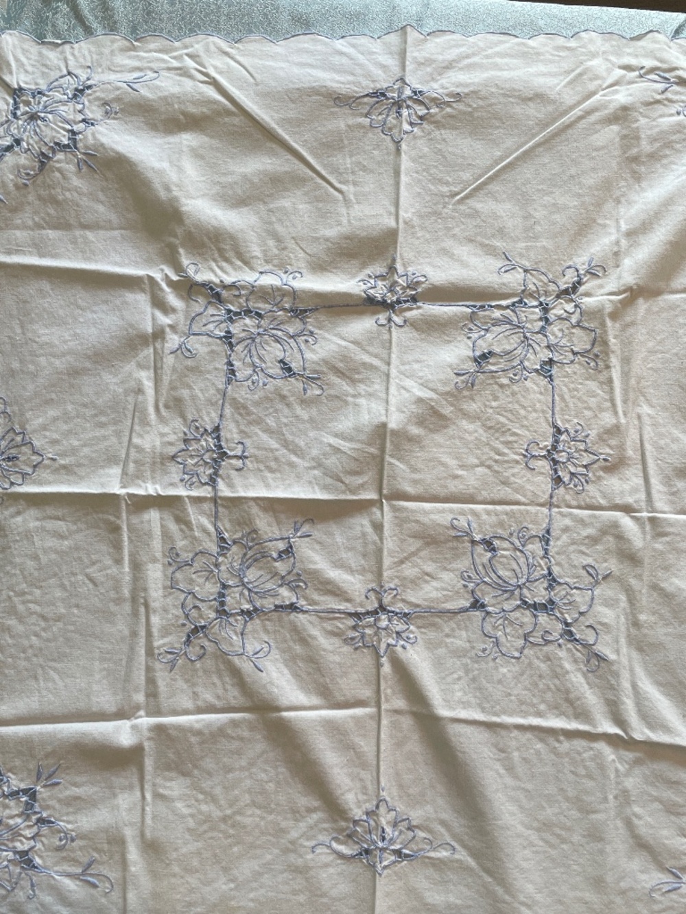vintage tablecloth featuring blue floral embroidery and scalloped edges.